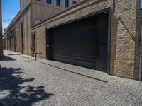 two windows in the side of a brick building, with a black garage door and brown door