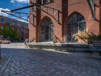 cobblestone driveway surrounded by modern buildings on sunny day with sun reflecting onto the windows