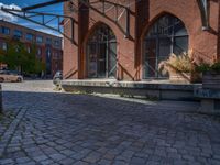 cobblestone driveway surrounded by modern buildings on sunny day with sun reflecting onto the windows