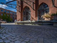 cobblestone driveway surrounded by modern buildings on sunny day with sun reflecting onto the windows