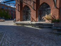 cobblestone driveway surrounded by modern buildings on sunny day with sun reflecting onto the windows