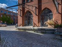 cobblestone driveway surrounded by modern buildings on sunny day with sun reflecting onto the windows