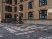 a brick courtyard has steps leading up to it, and a blue umbrella is on the ground