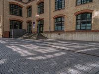 a brick courtyard has steps leading up to it, and a blue umbrella is on the ground