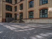 a brick courtyard has steps leading up to it, and a blue umbrella is on the ground