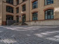 a brick courtyard has steps leading up to it, and a blue umbrella is on the ground