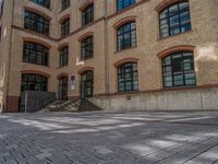 a brick courtyard has steps leading up to it, and a blue umbrella is on the ground