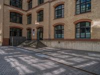 a brick courtyard has steps leading up to it, and a blue umbrella is on the ground