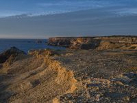 a lone lighthouse is perched on the edge of a cliff in front of the ocean