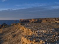 a lone lighthouse is perched on the edge of a cliff in front of the ocean