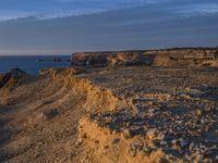 a lone lighthouse is perched on the edge of a cliff in front of the ocean