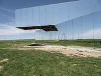 a picture of a huge mirror sitting on the grass in front of a building of mirrors