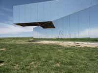 a picture of a huge mirror sitting on the grass in front of a building of mirrors