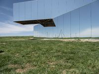 a picture of a huge mirror sitting on the grass in front of a building of mirrors