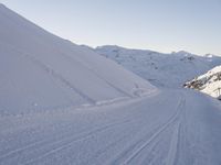 a snowboarder heading down a slope on a ski trail in the snow with mountains in the background