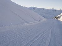 a snowboarder heading down a slope on a ski trail in the snow with mountains in the background