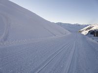 a snowboarder heading down a slope on a ski trail in the snow with mountains in the background