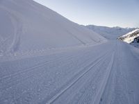 a snowboarder heading down a slope on a ski trail in the snow with mountains in the background