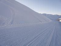 a snowboarder heading down a slope on a ski trail in the snow with mountains in the background