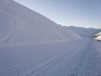 a snowboarder heading down a slope on a ski trail in the snow with mountains in the background