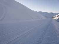 a snowboarder heading down a slope on a ski trail in the snow with mountains in the background