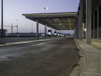 a view of an empty bus stop in the evening time with no people visible and an airport in the background