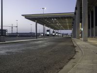 a view of an empty bus stop in the evening time with no people visible and an airport in the background