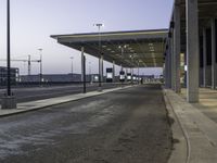 a view of an empty bus stop in the evening time with no people visible and an airport in the background