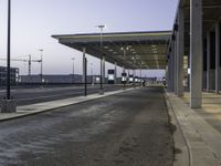 a view of an empty bus stop in the evening time with no people visible and an airport in the background