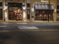 an empty street in the evening with cars parked outside a pizza shop in a city street