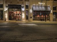 an empty street in the evening with cars parked outside a pizza shop in a city street