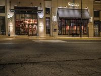 an empty street in the evening with cars parked outside a pizza shop in a city street