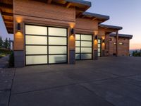 a garage area in the evening with lights on the side and two large garage doors on the inside