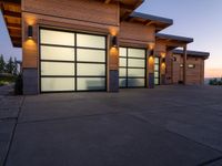 a garage area in the evening with lights on the side and two large garage doors on the inside