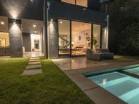 a patio and pool with an outdoor seating area in the evening lights shine through glass doors