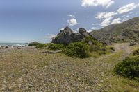 an expansive, rocky beach sits on the shore of a body of water with large rocks