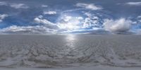 clouds floating over the snow covered ocean on a sunny day, while a polar bear walks by