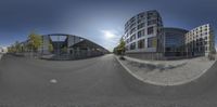 the panorama fish eye view of a building with curved glass walls next to a street