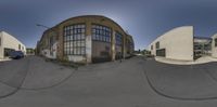 a fish eye lens shot of an industrial building and truck parking lot, with a street in front