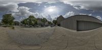 a street full of cars sitting next to a building under a cloudy sky in a fish eye view