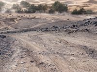 a truck on a dirt road in the desert with rocks and stones on the ground