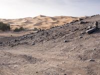 a truck on a dirt road in the desert with rocks and stones on the ground