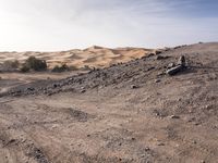 a truck on a dirt road in the desert with rocks and stones on the ground