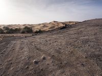 a truck on a dirt road in the desert with rocks and stones on the ground