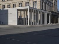 an exterior view of a building with pillars and a person walking on the sidewalk in front