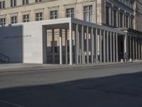 an exterior view of a building with pillars and a person walking on the sidewalk in front