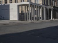 an exterior view of a building with pillars and a person walking on the sidewalk in front