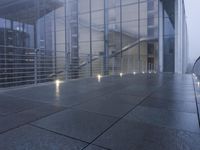an exterior view of an office building at night, with concrete slabs and stone flooring