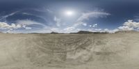 a view into a wide open plain of dirt with a sky background and clouds in the blue