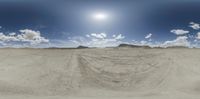 the sun is just shining over some sand dunes with a desert area on one side and mountains in the other